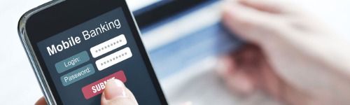 Man using debit card and mobile phone for online banking.