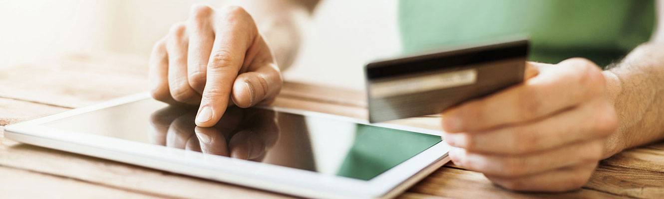 Man using credit card and tablet.