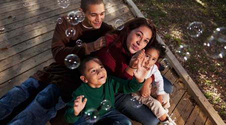 Young family playing with bubbles outside.